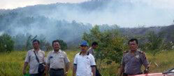 Sumampouw dengan latar belakang hutan lindung Batuangus yang terbakar (foto ist)