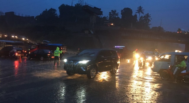 Di tengah guyuran hujan deras, petugas Sat Lantas Polres Minut mencoba mengurai kemacetan di Ring Road.