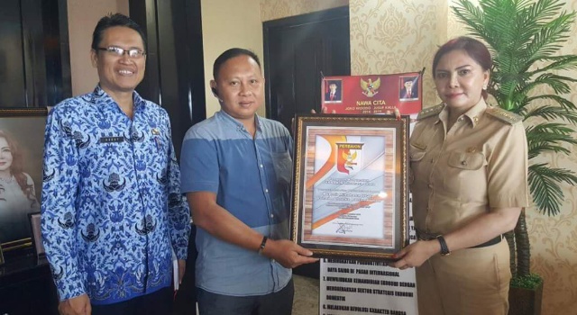 Ketua Perbakin Minut Novie Ngangi didampingi Ketua Panitia Robby Parengkuan menyerahkan piaga penghargaan kepada Bupati Minut Vonnie Panambunan.