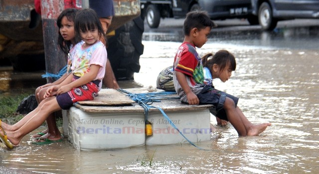 Anak-anak warga sekitar pun bermain di tengah genangan air sambil menunggu air surut