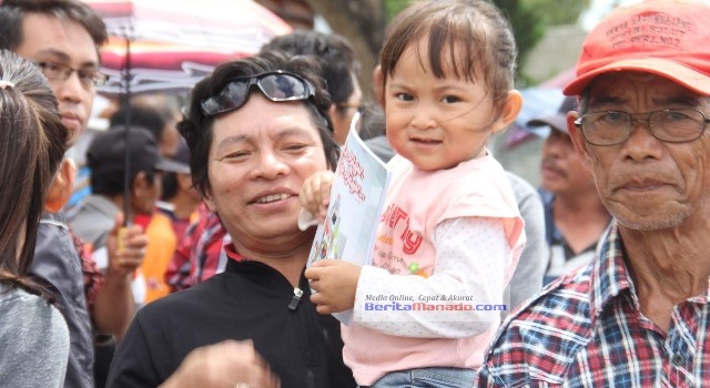 Digendong sang ayah, anak ini terlihat senang karena mendapat buku dari Presiden Jokowi