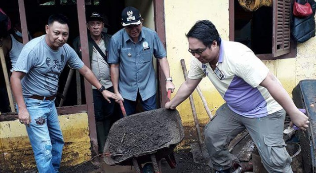 Pnt. Joppi Lengkong ikut membersihkan material pasir di rumah warga.