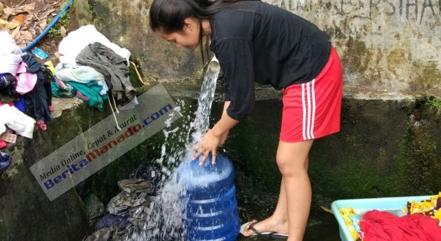 Anastasya Lensun saat menampung air di mata air desanya