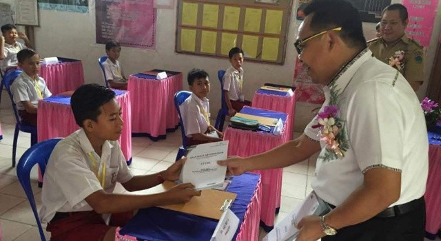 Wakil Ketua DPRD Minut Denny Wowiling membagikan naskah ujian bagi para siswa, sambil memberikan motivasi.(foto: Setwan DPRD Minut)