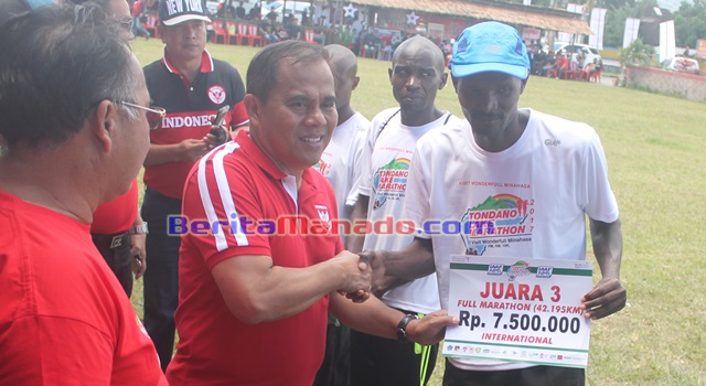 Bupati Minahasa Jantje Wowiling Sajow saat menyerahkan hadiah uang tunai kepada salah satu pemenang kategori 42 kilometer internasional