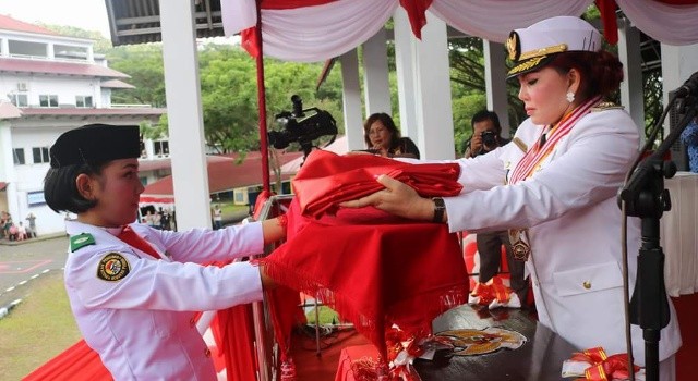 Irup Bupati Vonnie Panambunan menyerahkan bendera kepada Paskibra.(foto: Humas Pemkab Minut)