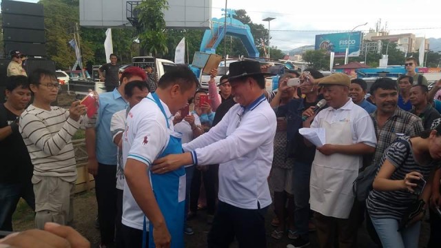 Walikota Manado Vicky Lumentut memakai celemek kepada asisten I Pemerintahan Kota Manado Mickler Lakat sebagai tanda di mulainy lomba masak.