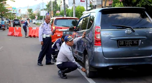 Petugas Dishub Manado sedang mengempeskan ban kendaraan yang parkir sembarangan