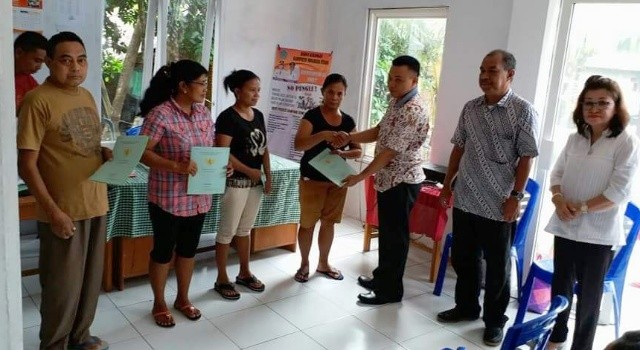 Hukum Tua Ponto Woddy Pangkey menyerahkan sertifikat tanah kepada masyarakat. 