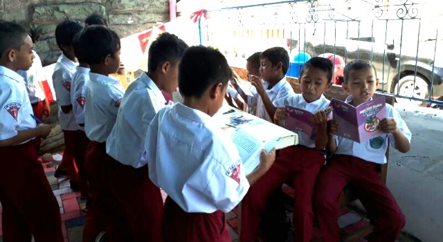 Para siswa sedang asik membaca buku yang ada di Rumah Cerdas Kelurahan Maasing