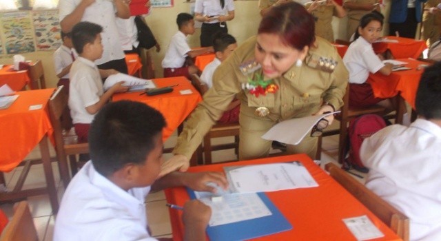 Bupati Vonnie Panambunan membagikan naskah ujian.(foto: Humas Pemkab Minut)