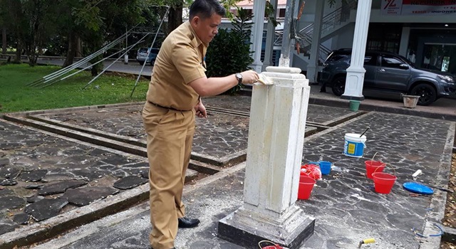 Vicky Tanor saat sedang melakukan pengecatan penyangga tiang bendera Sekretariat DPRD Minahasa