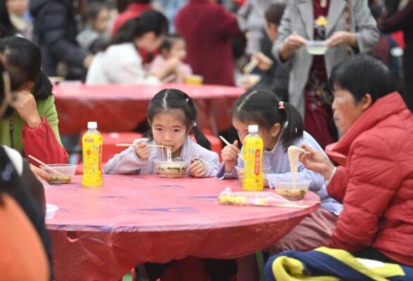 Anak-anak mencicipi mi beras Shengzha dalam sebuah ajang kompetisi keahlian warisan budaya takbenda di Wilayah Otonom Etnis Yao Dahua yang berada di Kota Hechi, Daerah Otonom Etnis Zhuang Guangxi, China selatan, pada 21 Maret 2026. (Xinhua/Huang Xiaobang)