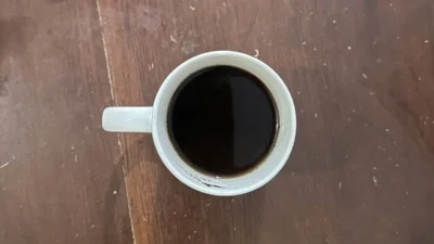 Segelas kopi hitam tanpa gula di atas meja, terkait batas aman minum kopi untuk kesehatan jantung