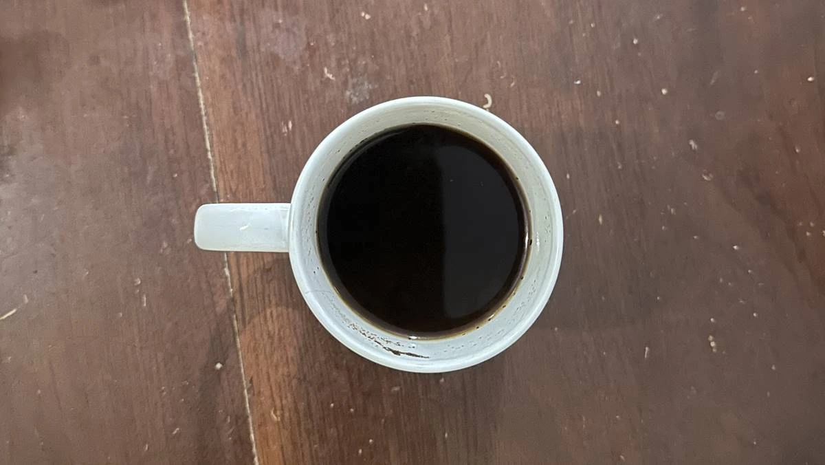 Segelas kopi hitam tanpa gula di atas meja, terkait batas aman minum kopi untuk kesehatan jantung