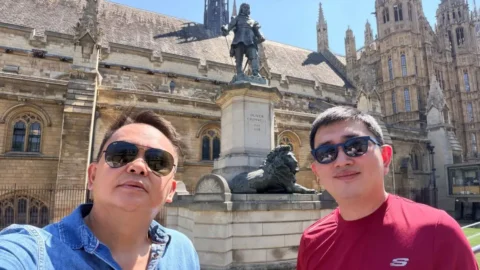 Rocky Wowor dan Medy Lensun berfoto di depan Istana Westminster atau Gedung Parlemen Inggris di London, dengan Patung Oliver Cromwell di area Parliament Square.
