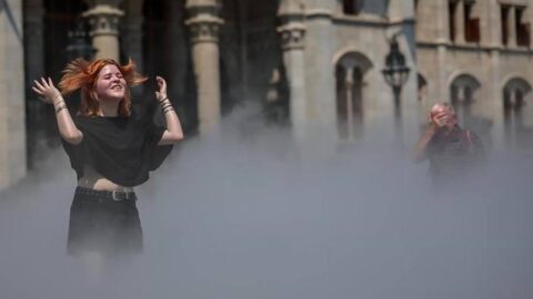 Seorang wanita menyejukkan diri di bawah sistem pendingin kabut saat gelombang panas terjadi di Budapest, Hongaria, pada 24 Juni 2026.