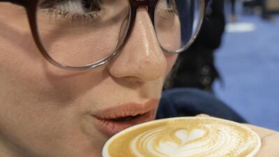 Seorang wanita minum secangkir kopi dengan hiasan latte di atasnya dalam ajang Restaurants Canada Show (RC Show) 2026 di Mississauga, Ontario, Kanada, pada 8 Maret 2026. (Xinhua/Zou Zheng)