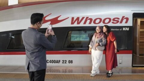 Penumpang berpose dengan latar Kereta Cepat Whoosh di Stasiun Halim Jakarta