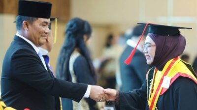 Gubernur Yulius Selvanus bersalaman dengan seorang wisudawan perempuan pada kegiatan perguruan tinggi BMR di Kotamobagu.